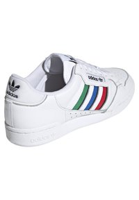 Fehér bőr sneaker három függőleges csíkkal zöld, kék és piros színben, fekete logóval a saroknál és perforált díszítésekkel.