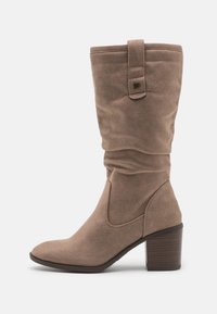 Bottes en daim taupe hautes avec un design froissé, bout pointu et un talon empilé. Présente une sangle et un détail de boucle en haut.