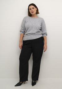 Gray knitted sweater with rolled sleeves, paired with black wide-leg trousers and pointed black heels. Smooth texture and relaxed fit.