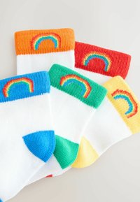 Quatre paires de chaussettes en coton avec des corps blancs et des bordures côtelées colorées. Les bordures sont orange, rouge, verte et jaune, chacune avec un arc-en-ciel brodé.