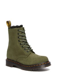 Olijfgroene veterschoenen tot de enkel met zwarte zool, oranje stiksel, donsachtige zwarte binnenkant en gele trekband bij de hak.