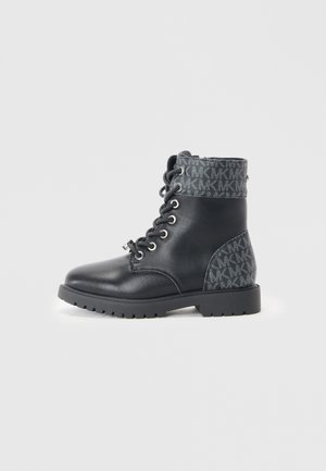 Bottines noires avec un dessus en cuir brillant, un revers en tissu à motif gris, des œillets en métal et une semelle en caoutchouc texturé.