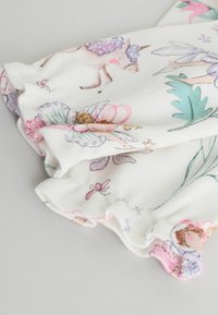 Biała tkanina z pastelowymi ilustracjami wróżek, jednorożców, kwiatów i liści, z zebranym brzegiem i falbaną.