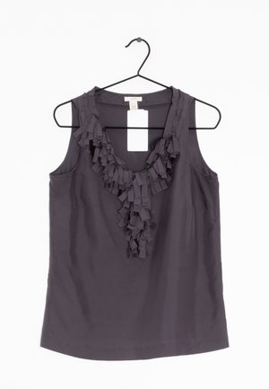 Blouse sans manches gris foncé avec un détail volanté au niveau de l'encolure en V, suspendue sur un cintre noir sur fond blanc.