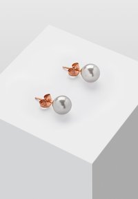 Perle øredobber med rosegull hardware. Runde hvite perler på et hjerteformet feste. Glatt tekstur og polert finish.