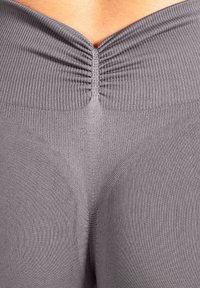 Leggings gris côtelés avec une taille froncée et une texture lisse. Présentent un léger effet sculptant autour de la zone arrière.