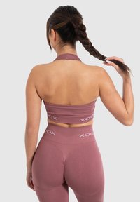 Biustonosz sportowy typu ladle oraz legginsy o wysokim stanie w stonowanym mauve, z przewężonym teksturem, z haftowanym logo wzdłuż pasa.