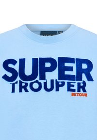 Hellblaue Sportjacke mit "SUPER TROOPER" in dunkelblauen, flauschigen Buchstaben und "RETOUR" in Orange, runder Halsausschnitt und weicher Stoffstruktur.