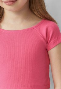 Roze geribbelde top met korte mouwen en een wijde halslijn. Heeft een zachte textuur en gestikte zoomdetails.