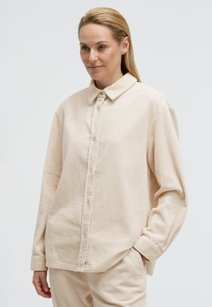 Helle beige Kordhosen-Hemd mit Knopfleiste, klassischem Kragen, strukturiertem Stoff und langen Ärmeln, das eine lockere Passform und feine Rippung aufweist.