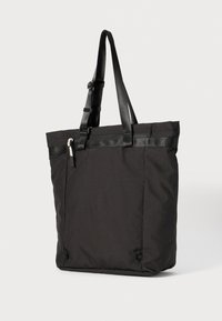 Sort totebag, fremstillet af slidstærkt stof, med en flad top, justerbare stropper og en glat, mat tekstur med hardware detajler på siden.