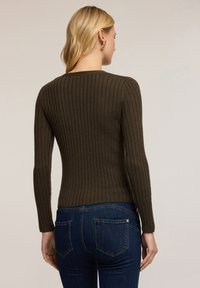 Mörk olivgrön ribbad långärmad tröja med tight passform och rund halsringning, tillsammans med mörkblå jeans och subtil detaljer bak.