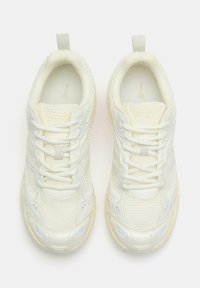 Sneakers atletici bianchi con tomaia in rete testurizzata, accenti rinforzati e suola di colore chiaro. Presentano lacci e collo imbottito.