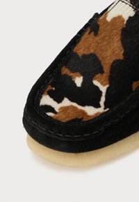 Fekete velúr mokaszin barna és fehér állatmintás textil felső résszel, puha bézs gumitalppal és részletes varrással.