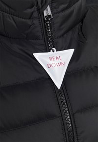Zwarte pufferjas met ritssluiting en een gestructureerd oppervlak. Een wit label met de tekst "REAL DOWN" is duidelijk zichtbaar.