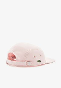 Gorra rosa con visera curva, hecha de tejido texturizado. Cuenta con un logo de cocodrilo verde bordado y una correa ajustable en la parte posterior.