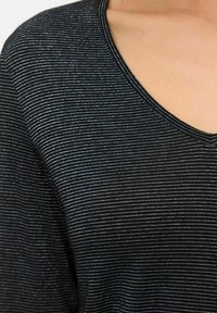 Černobíle pruhované tričko s výstřihem do V a krátkým rukávem, které se vyznačuje jemnou texturou a subtilním leskem látky.
