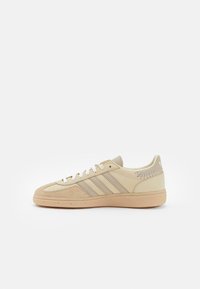 Beige Wildleder- und Ledersneaker mit drei beigen Streifen, strukturierter Zehenkappe und einer Sohle aus Gummi. Mit Schnürsenkeln und Steppnähten.