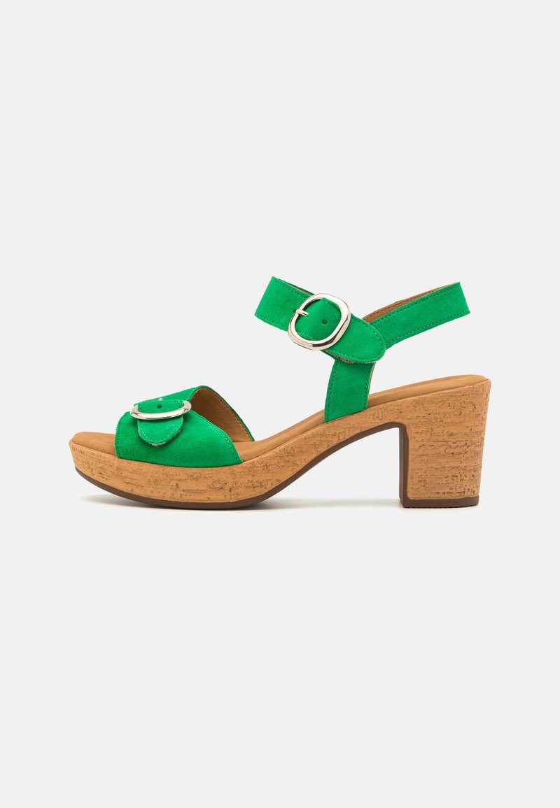 Sandale femme en daim vert avec talon bloc en liège, bride de cheville ajustable et détail boucle argentée sur les brides avant et de cheville.