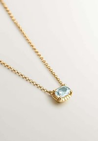 Collar de cadena de oro que presenta una gema rectangular de color azul claro. Gema engastada en un bisel de oro decorativo con acentos texturizados.