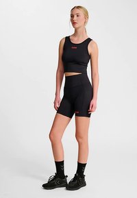 Svart atletiskt kort linne och shortsset i stretchigt material, med en röd logotypdetalj. Matchat med svarta sportskor och strumpor.