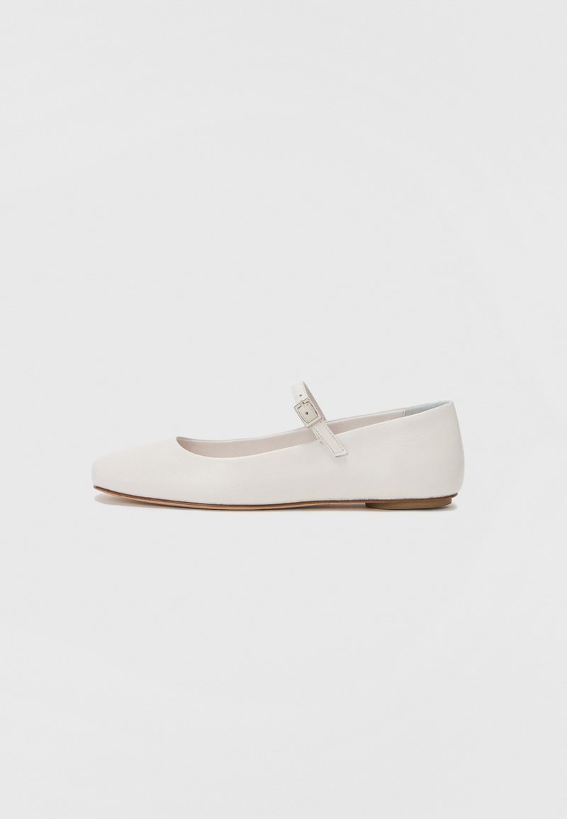 Vita läderballerinas med rund tå och en sidospänne. Slät textur, platt sula och minimalistisk design.