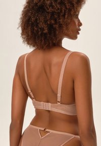 Jasnoróżowy zestaw bielizny o gładkiej fakturze, składający się z prostego biustonosza z regulowanymi ramiączkami i zapięciem na haftkę z tyłu.