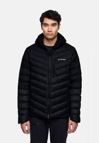 Schwarze gesteppte Jacke mit durchgehendem Reißverschluss, Kapuze und diagonalem Chevron-Muster. Enthält eine Brusttasche und das Markenlogo auf der linken Schulter.