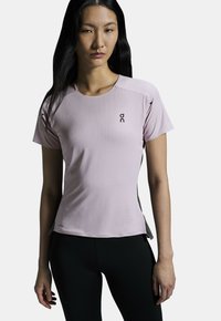 Light pink athletic t-shirt with short sleeves, round neckline, and black logo. Soft fabric, fitted design, contrasting side panels.