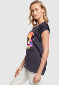 Mørkegrå T-shirt med et farverigt grafik af en solnedgang, palmer og teksten "Sommer", lavet af blødt stof med en afslappet pasform.