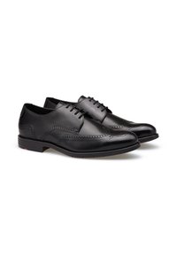 Chaussures habillées en cuir noir avec un design classique à bout fleuri, des détails perforés, une pointe ronde et une semelle en caoutchouc plate pour une meilleure adhérence.