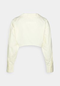 Camisa de mangas compridas cortada em amarelo claro, feita de algodão suave. Apresenta um colarinho clássico e punhos com botões.