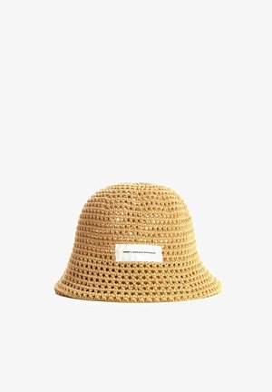 Sombrero tipo bucket tejido en color beige con una etiqueta rectangular blanca que dice “mwwm x mod wave movement” sobre un fondo blanco.