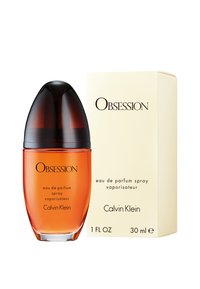 Appelsinparfymeflaske med avrundet design, svart lokk og klar bunn, ved siden av en kremfarget eske med "Obsession"-etikett og Calvin Klein-merke.