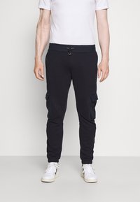 Tmavě modré tepláky s elastickým pasem a stahovací šňůrkou, s bočními cargo kapsami a ribbrovanými manžetami, vyrobené z měkké látky.