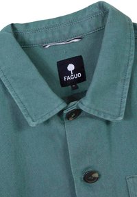 Green denim shirt with a collared neck, featuring black buttons and a tag that reads "FAGUO." Textured fabric with a ribbed pattern.