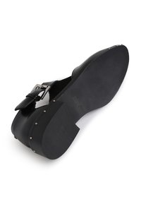 Schwarzer Lederschuh mit einem breiten Knöchelriemen und einer Metall-Schnalle, verziert mit silbernen Nieten und einer strukturierten Gummisohle.