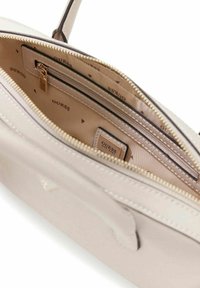 Sac à main beige clair avec ferrures dorées, doté d'une fermeture éclair sur le dessus, de plusieurs compartiments intérieurs et d'une doublure à motifs avec logo répété.