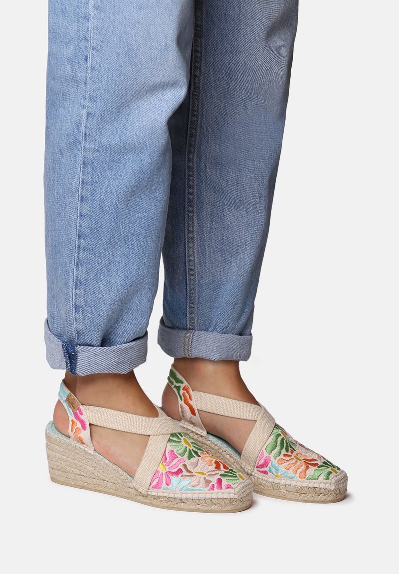 Sandalias de cuña bordadas con suela de yute natural, que presentan patrones florales en rosa, verde y naranja sobre una base beige clara.