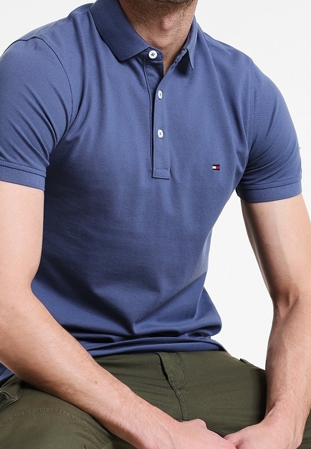 Granatowa koszulka polo z mieszanki bawełny, z klasycznym kołnierzykiem, krótkimi rękawami i małą naszywką z logo na piersi. Gładka faktura.