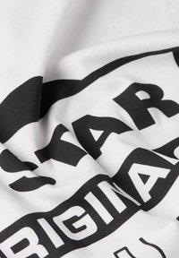 Witte katoenstof met grote zwarte bedrukte tekst. De stof lijkt zacht en iets gestructureerd, met een gedurfde grafische vormgeving.