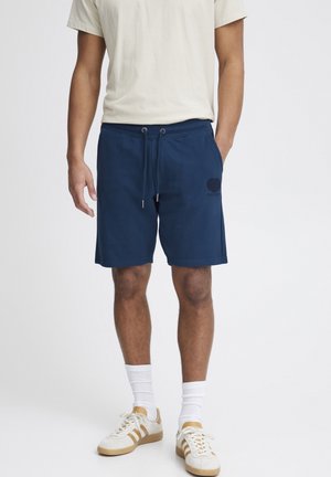 Pantalones cortos de algodón azul marino con cintura elástica, cordón y bolsillos laterales. Presentan un sutil logotipo en forma de corazón en el muslo izquierdo.