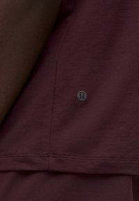 Bordo atletska majica s zaobljenim donjim rubom, mekog tekstila i malim crnim logotipom smještenim na bočnoj šav.