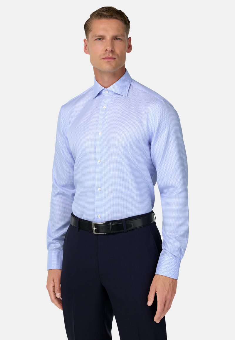 Lichtblauw geruit overhemd met een puntige kraag, knoopsluiting aan de voorkant, lange mouwen en een gladde textuur. Gepaard met donkere broeken en een zwarte riem.