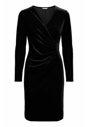 Zwarte fluwelen jurk met lange mouwen, V-hals en geraffineerde details bij de taille. Behoudt een soepele textuur met een lengte tot de knie.