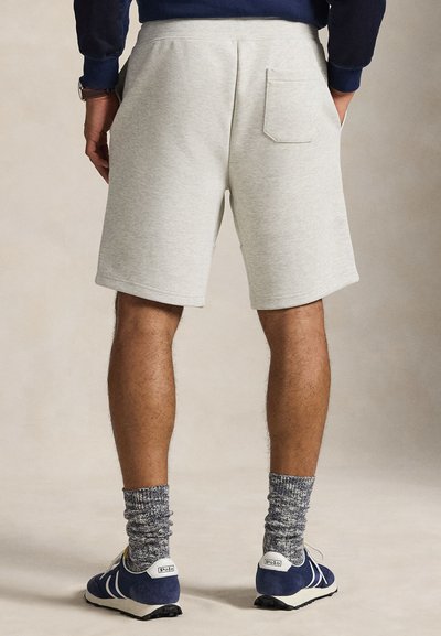 Ανοιχτόγρινα βαμβακερά σορτς με πίσω τσέπη, σε συνδυασμό με ναυτικά παπούτσια και υφασμένα γκρι κάλτσες. Απλός σχεδιασμός με αθλητικό στυλ.