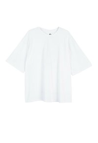 Biała, oversize koszulka z krótkim rękawem i okrągłym dekoltem, w luźnym kroju, prezentowana na jednolitym białym tle.