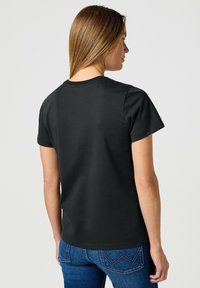 Camiseta de algodón negra de manga corta y cuello redondo, con una textura suave y una silueta ajustada.