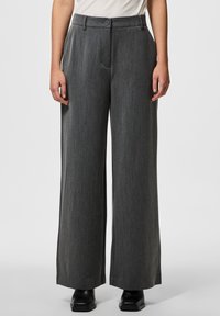 Pantaloni a gamba larga in un tessuto grigio testurizzato, con chiusura a bottone e pieghe frontali. L'orlo è leggermente svasato.