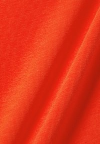 Tessuto rosso brillante con una superficie liscia, caratterizzato da fini righe e una leggermente lucida, che si adagia in onde morbide.